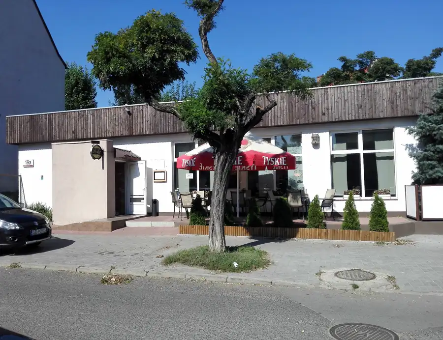 Biały budynek restauracji z ogródkiem przy ulicy