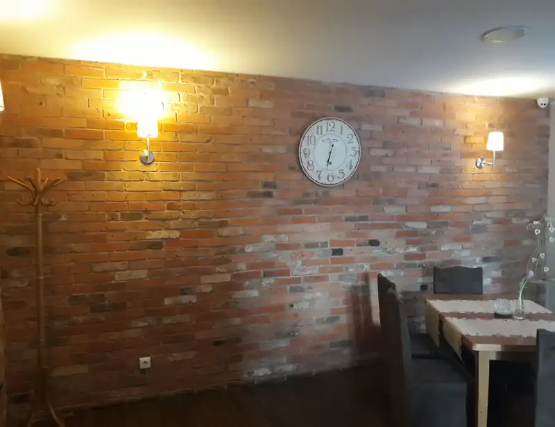 Sala z ceglaną ścianą, kinkietami i zegarem